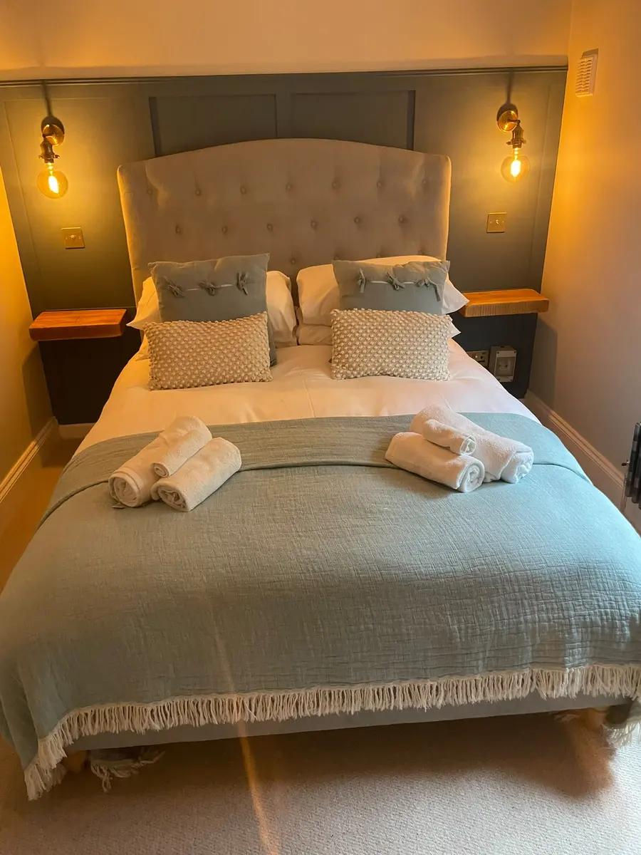 Freshly made double bed with folded towels in a guest bedroom