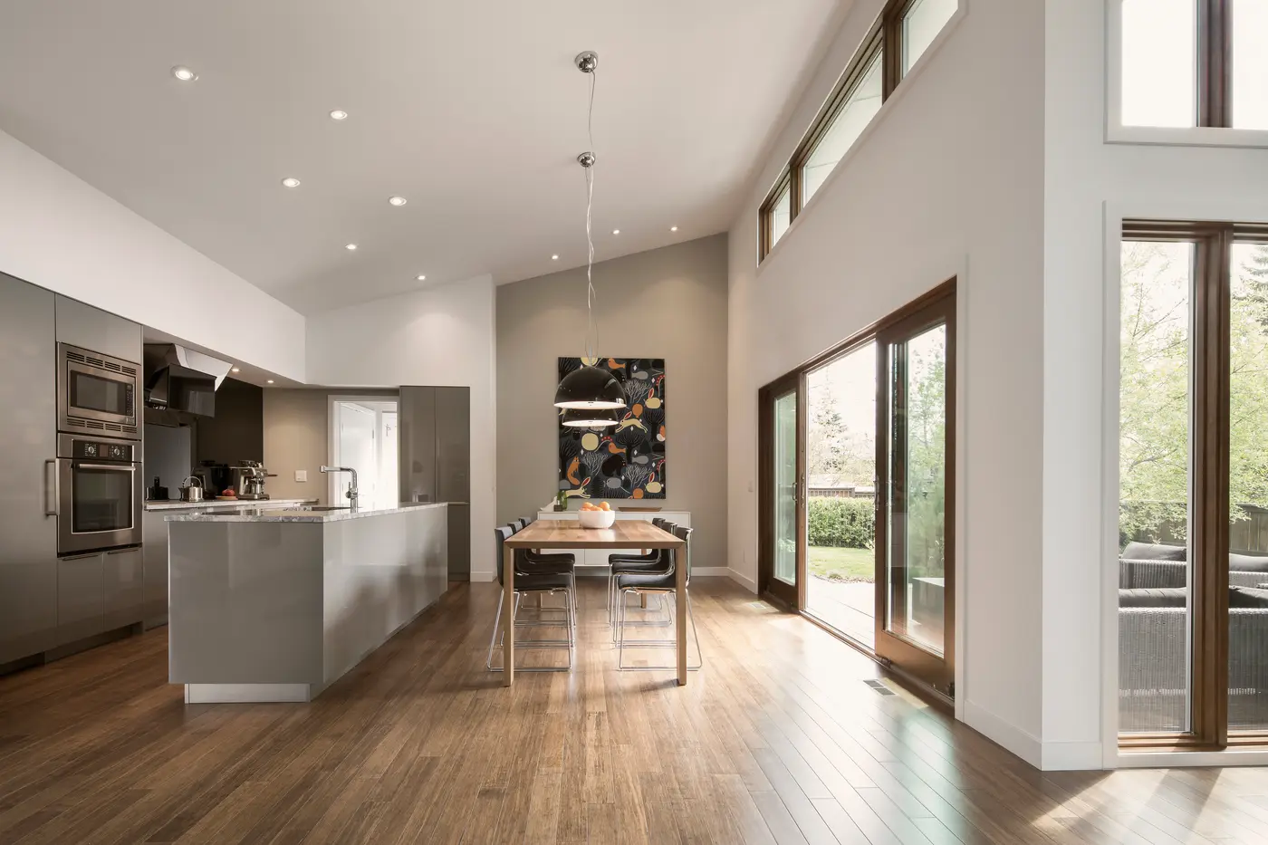 Open plan kitchen and dining area with a long table and tall windows