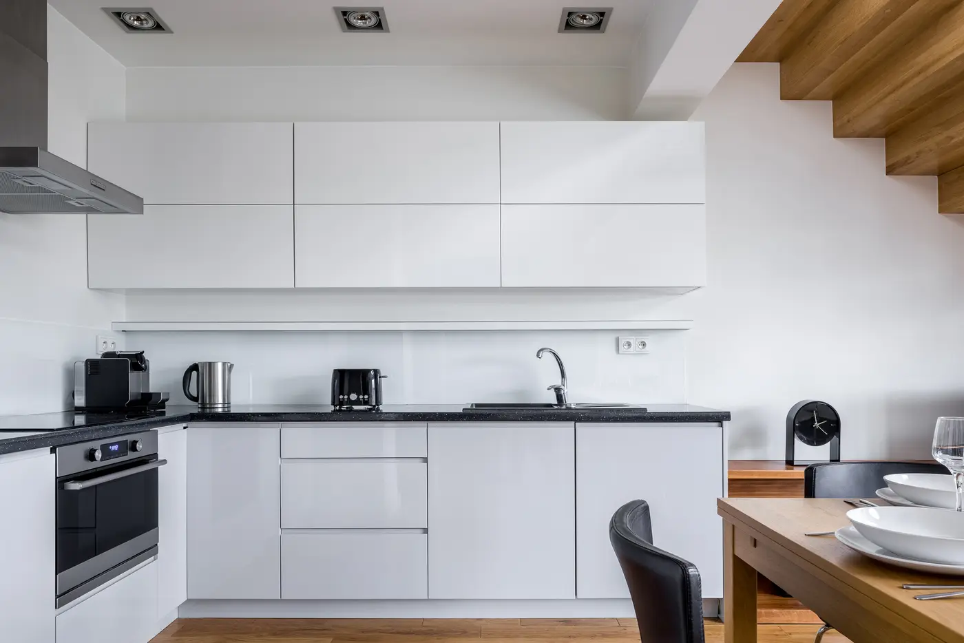 Bright white kitchen with a dining table and stairs behind